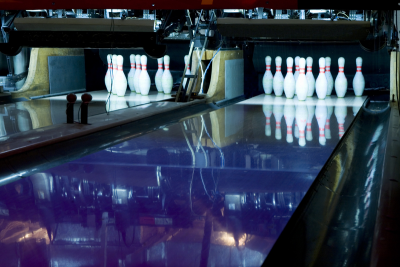 photo of bowling lane in the dark with pins illuminated